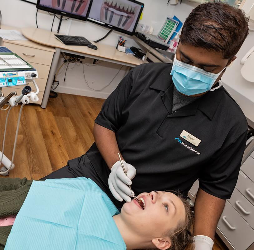 Dental Hygienist examining a patient's teeth in the dental chair