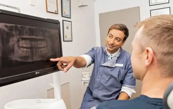 Dentist pointing to a clear X-ray on the monitor for patient